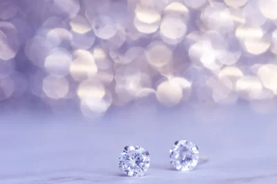 How to clean diamond earrings: sparkling diamond studs on a lilac background