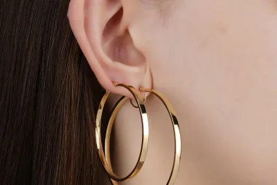 Luxury hoop earrings in polished yellow gold worn on the ear