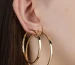 Luxury hoop earrings in polished yellow gold worn on the ear