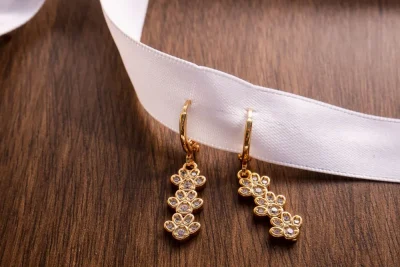 Gold flower earrings on a wooden table, a look close to Van Cleef Frivole earrings