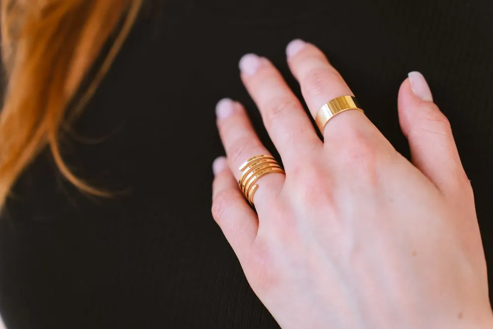 Gold band rings on a woman's hand, showing how stacked rings look when worn