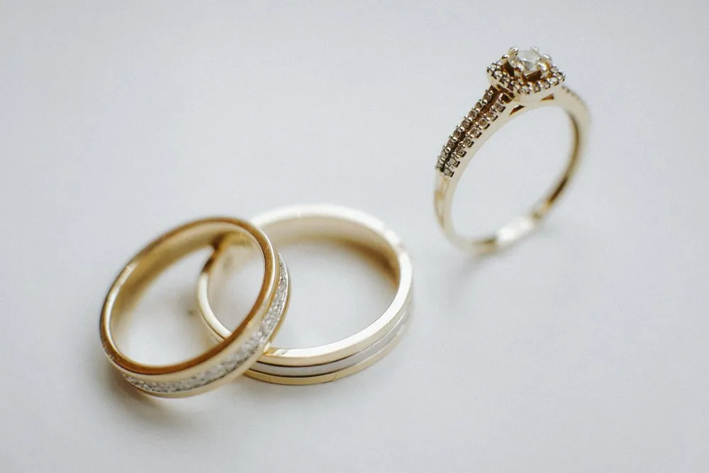 Cartier Love ring vs wedding band: two gold wedding bands and a diamond engagement ring side by side