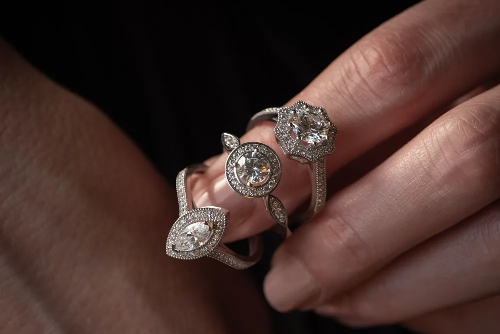 Diamond rings held on a hand, similar to a Cartier Love ring with diamonds