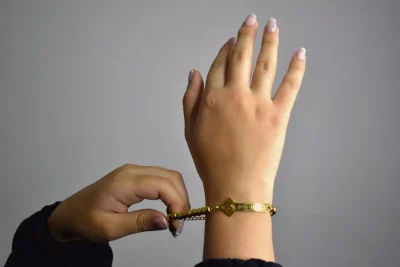 Van Cleef Alhambra vs Cartier Love bracelet comparison: hands adjusting a gold bracelet