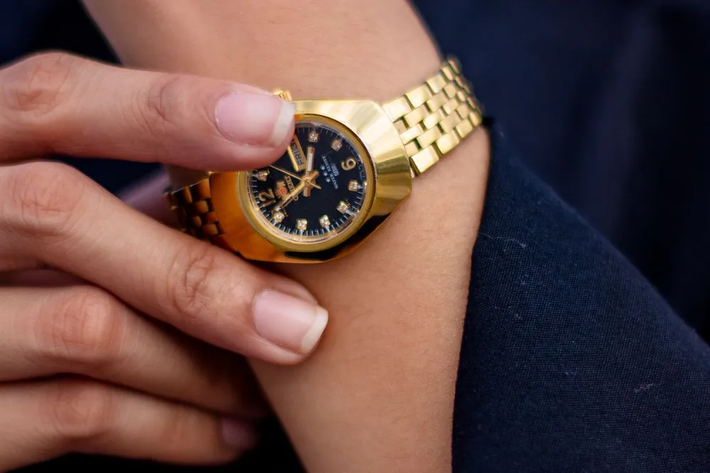 Cartier Panthere watch strap adjustment: hand adjusting a gold link bracelet wristwatch