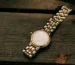 Vintage Cartier Santos in Dubai: a vintage gold watch with a bracelet resting on a dark wooden surface