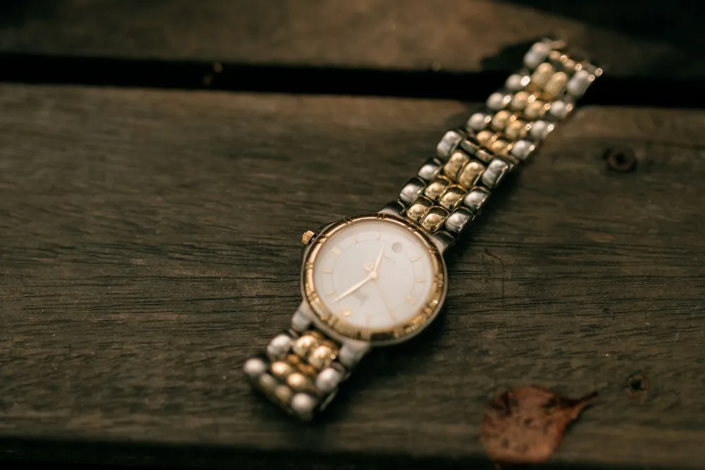 Vintage Cartier Santos in Dubai: a vintage gold watch with a bracelet resting on a dark wooden surface