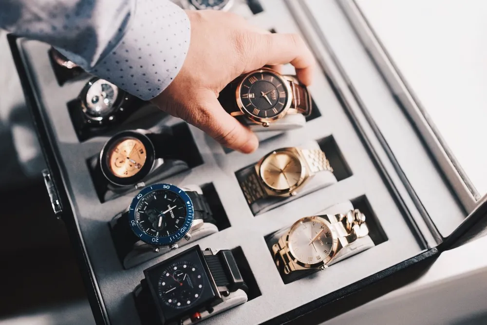 Luxury watch valuation in Dubai: a hand picking one watch from a display case of luxury watches