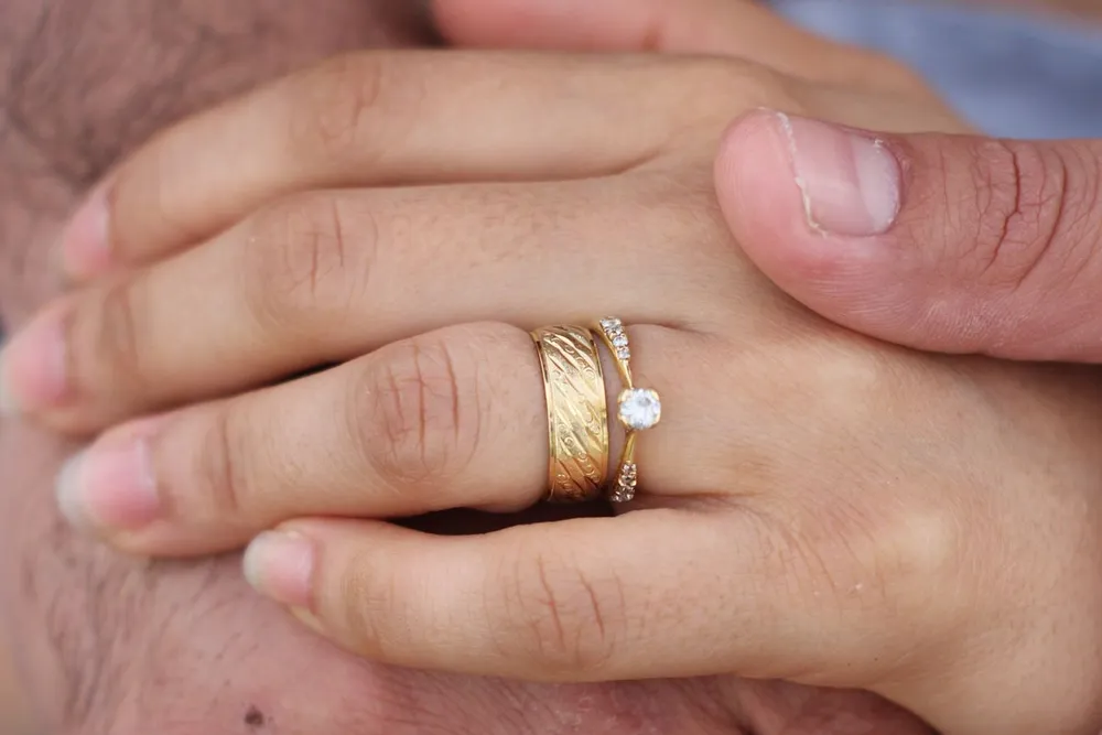 Cartier Love ring vs wedding band: two hands wearing plain gold wedding bands and a diamond ring
