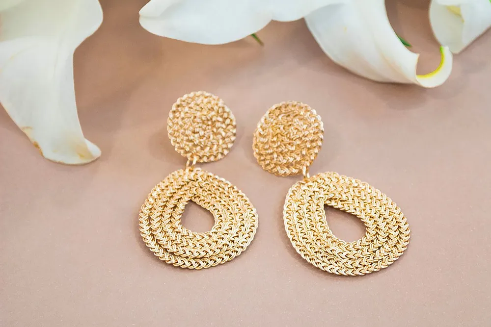Gold earrings beside a white lily, a soft look close to Van Cleef Frivole earrings