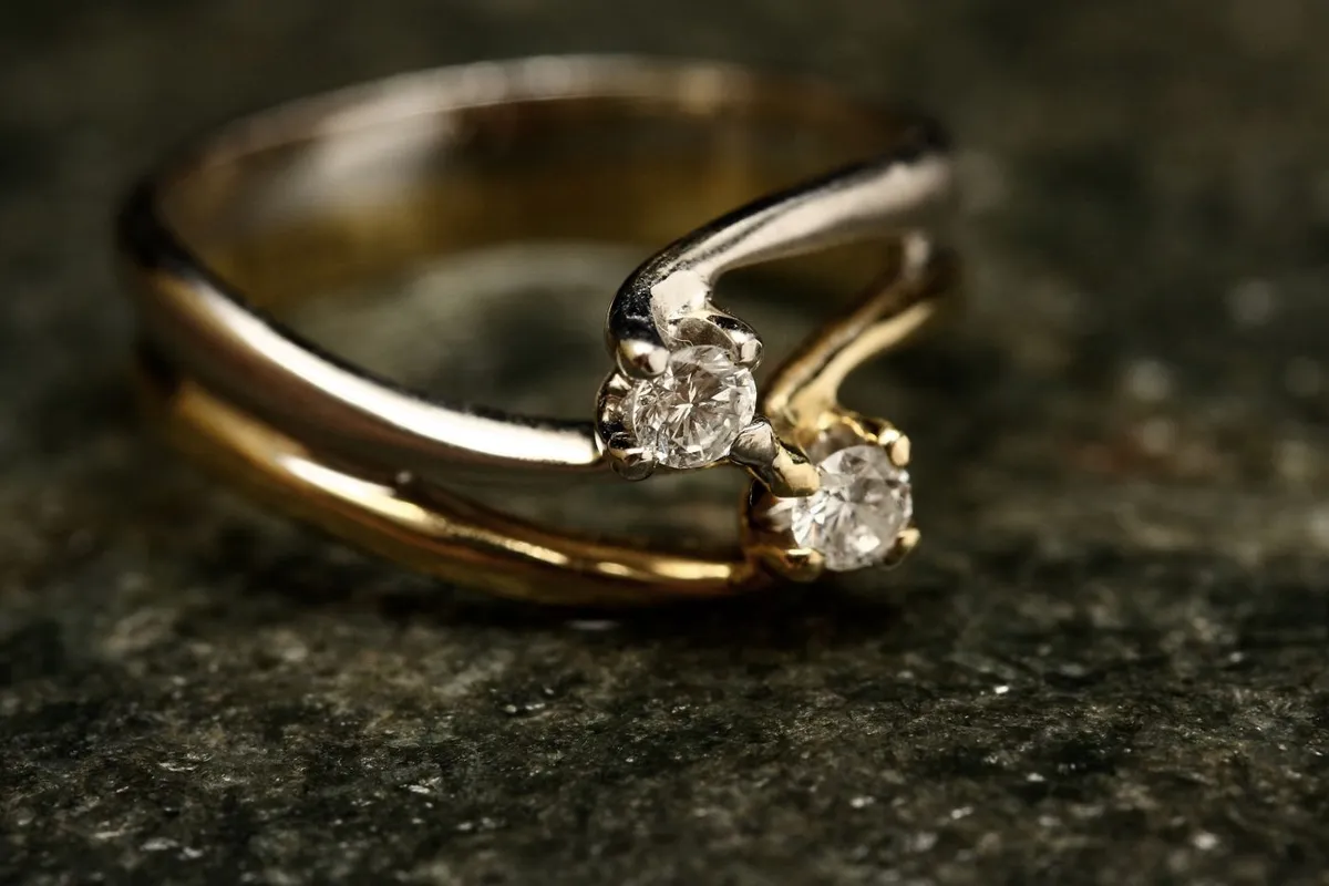 Van Cleef Alhambra ring style gold band with two diamonds on dark stone